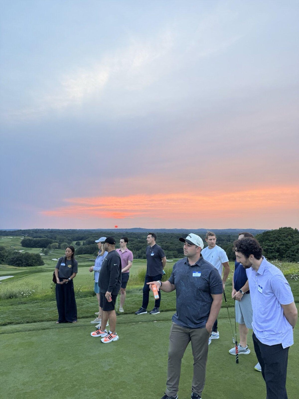 Attendees talking on the course at sunset