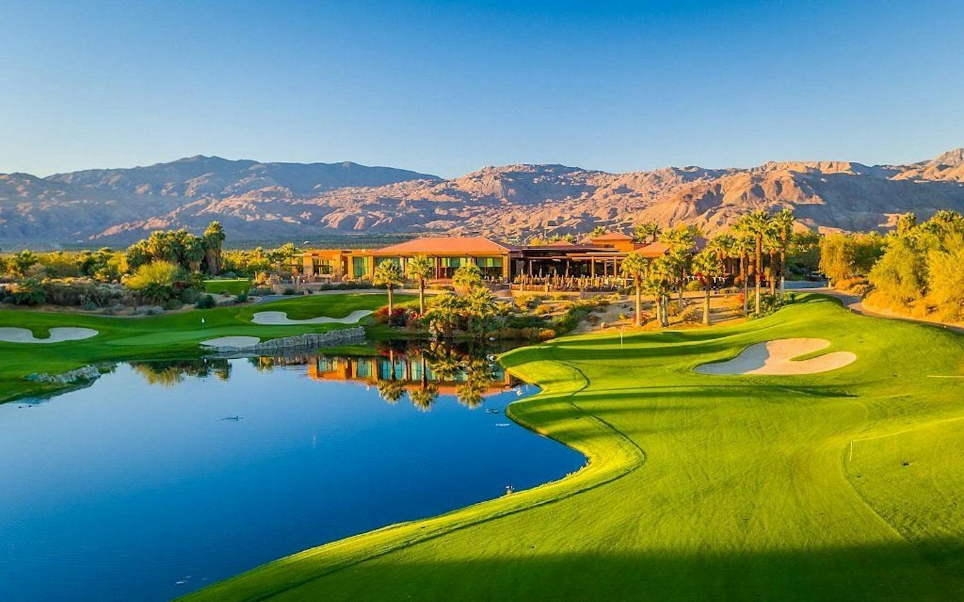 A lake and green below the clubhouse at Desert Willow, with desert mountains behind